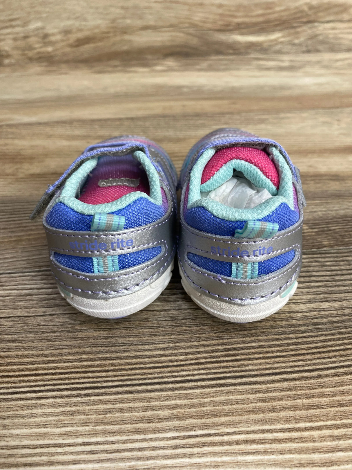Pair of Stride Rite toddler sneakers in purple, blue, and pink on wood background