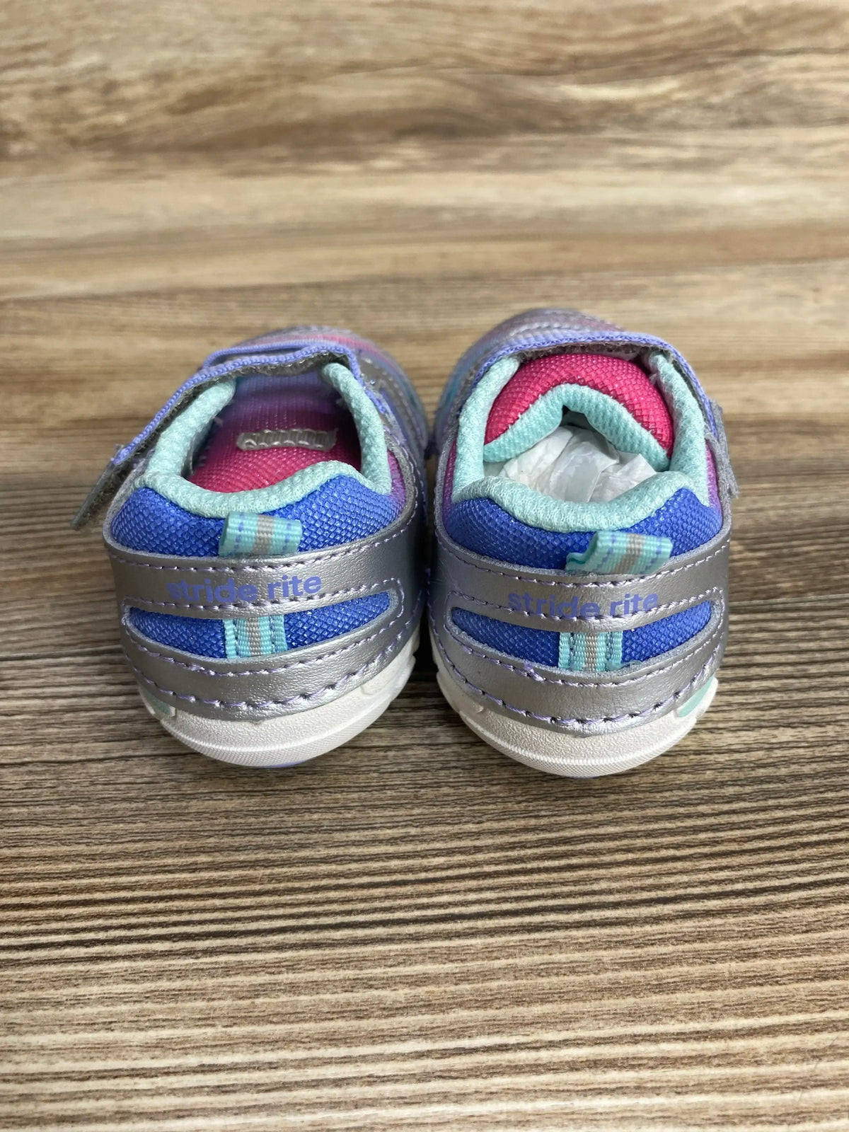 Pair of Stride Rite toddler sneakers in purple, blue, and pink on wood background
