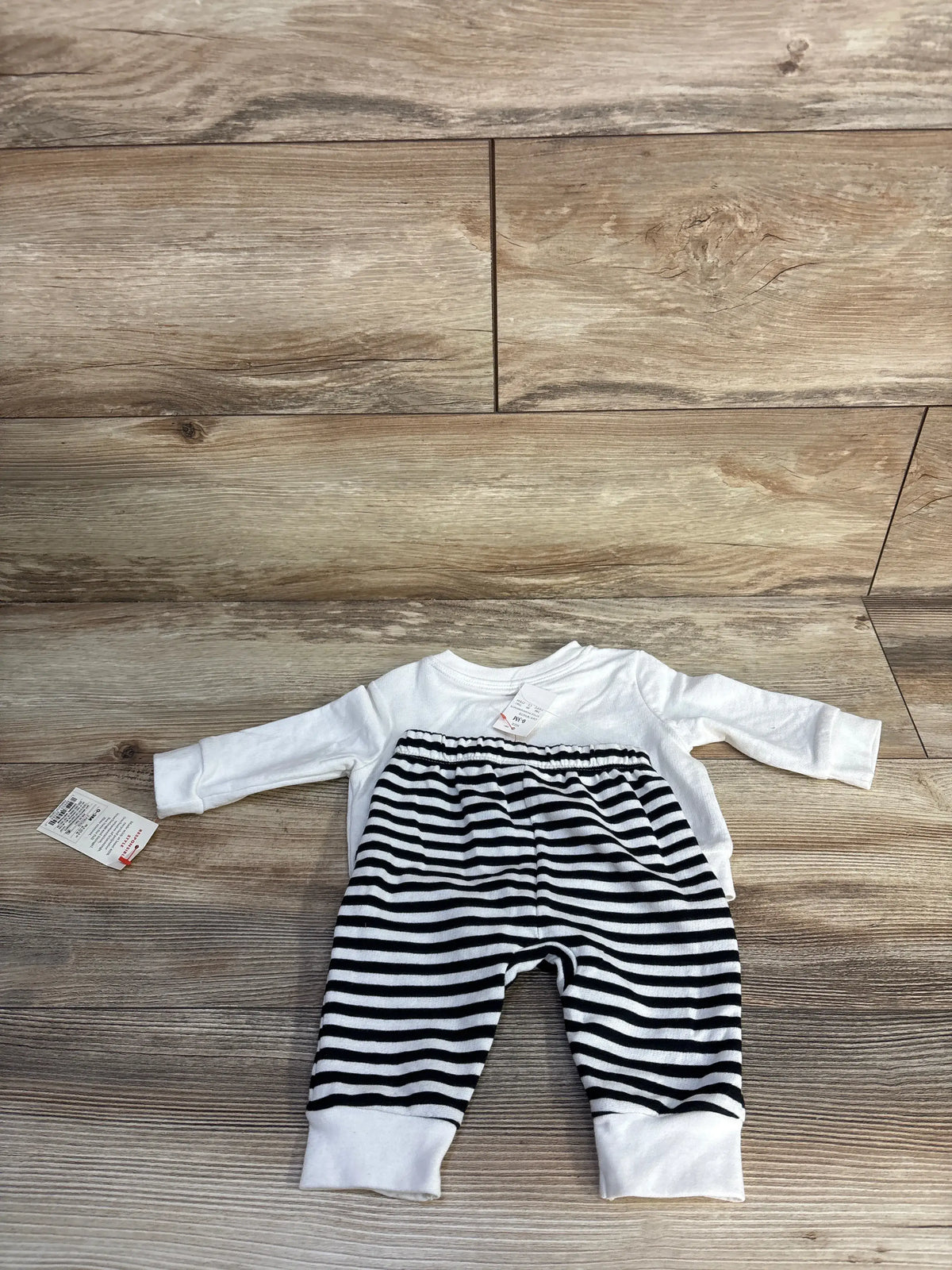 Top view of Cat & Jack Halloween sweatshirt and joggers set showcasing white sweatshirt and black-and-white striped joggers on a wood-look floor