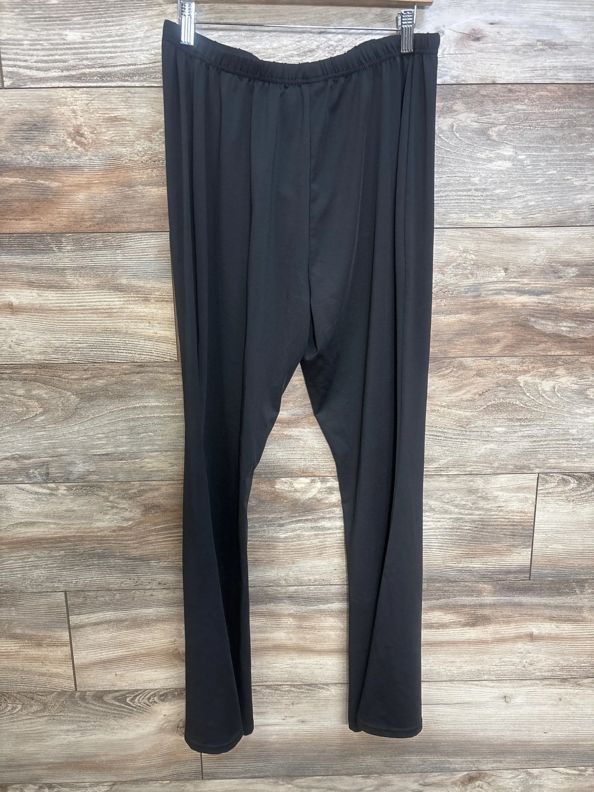 Front view of black maternity over belly yoga pants in size XL showcasing the over belly waistband with a wood plank background