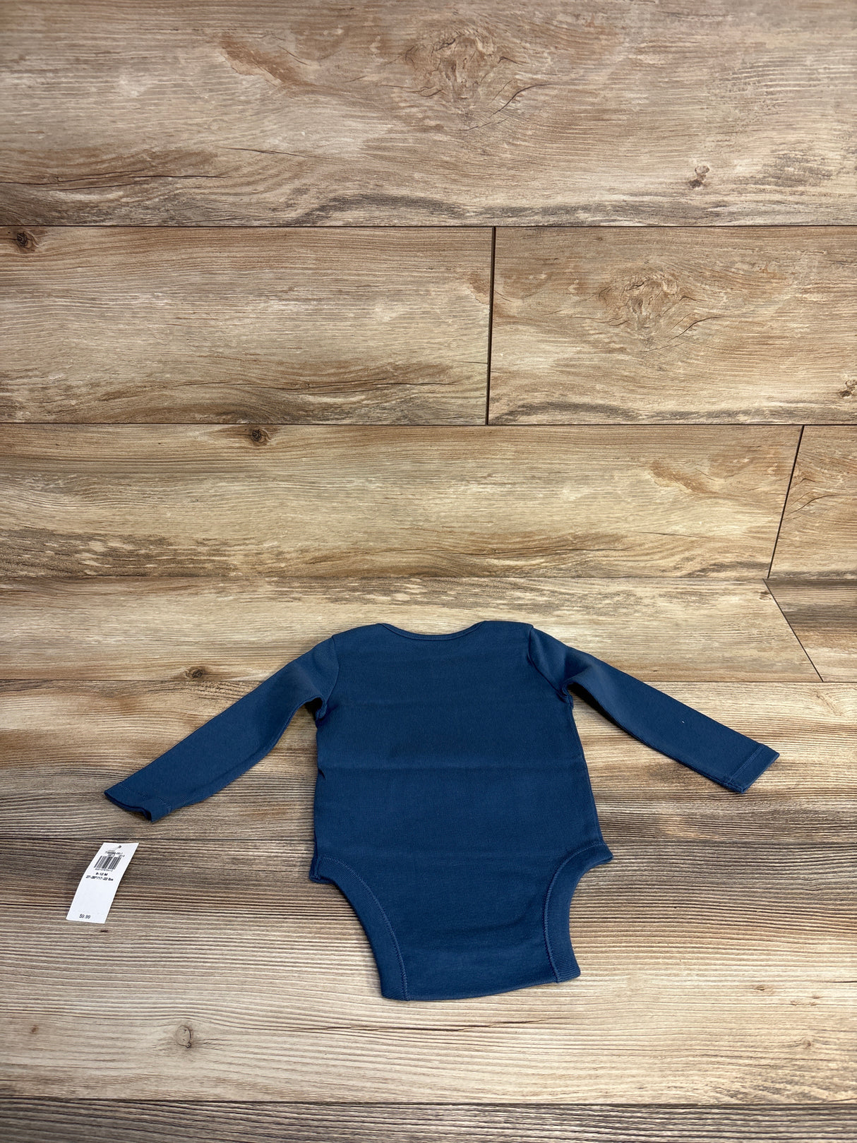 Navy blue long-sleeve baby onesie laid flat on wooden surface, children's clothing resale