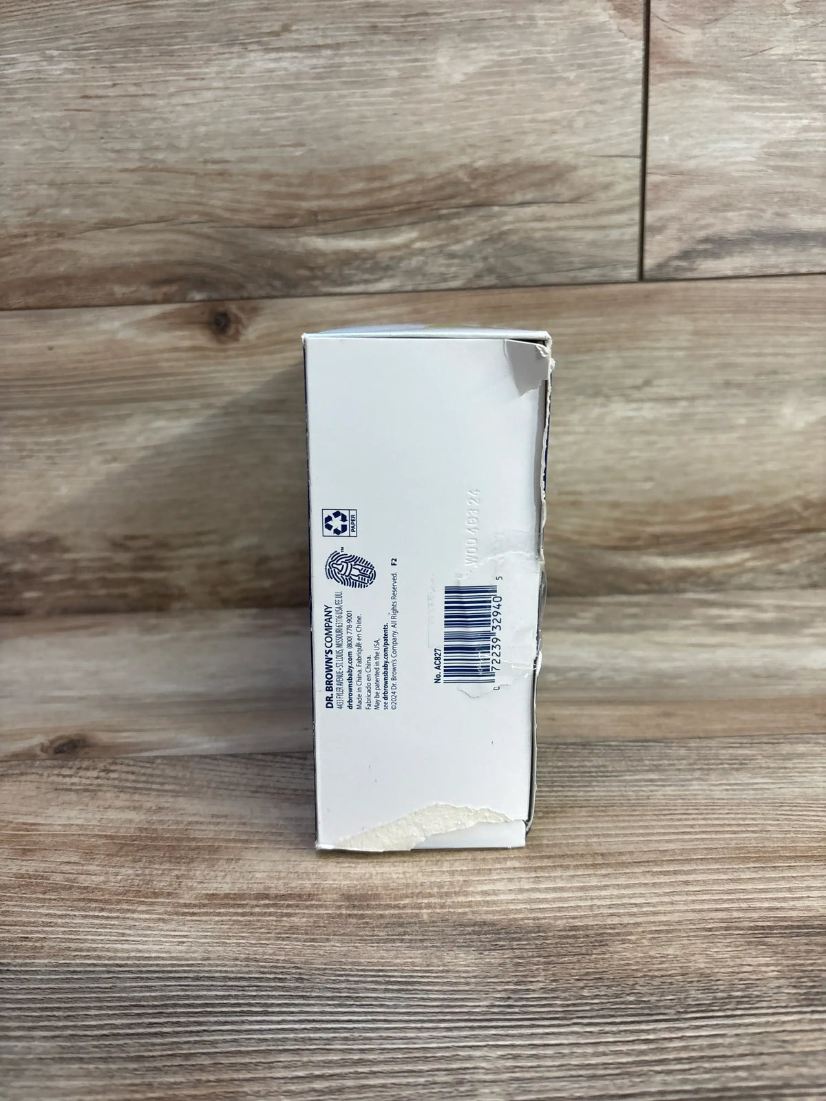 Side view of Dr. Brown's dishwasher basket box for narrow baby bottle parts with barcode and torn corner on wood background