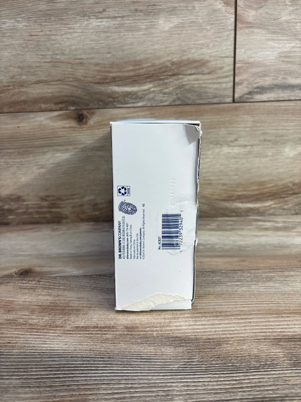 Side view of Dr. Brown's dishwasher basket box for narrow baby bottle parts with barcode and torn corner on wood background