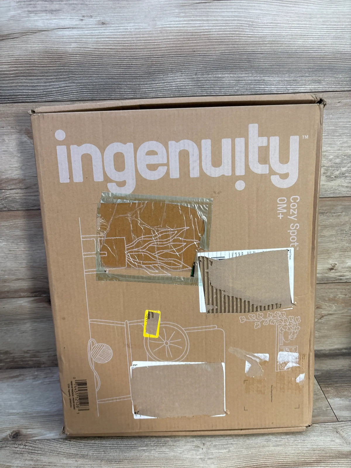 Front view of Ingenuity Cozy Spot reversible duvet activity gym packaging with product illustrations on a wood floor