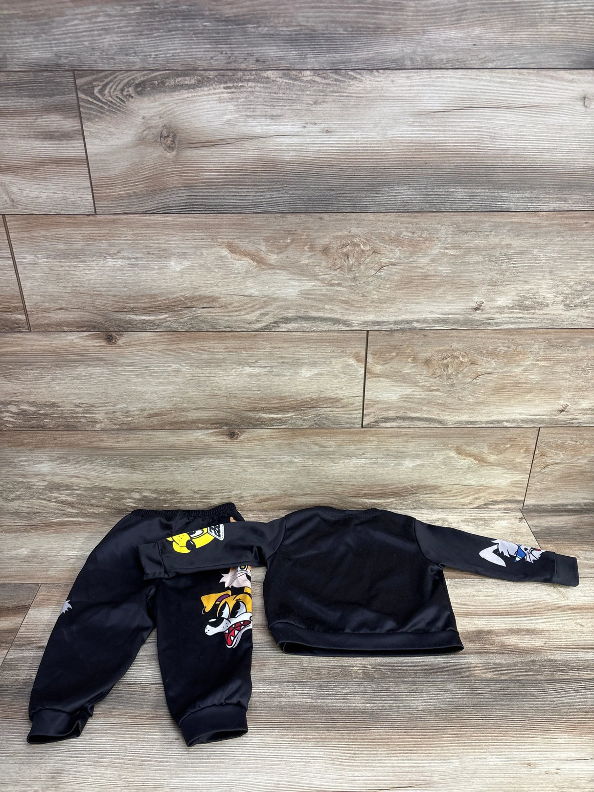 Black toddler cartoon character sweatshirt and pants set on wooden background