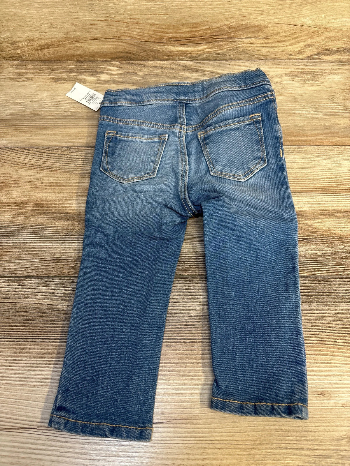 Blue denim toddler jeans with back pockets displayed on wood surface