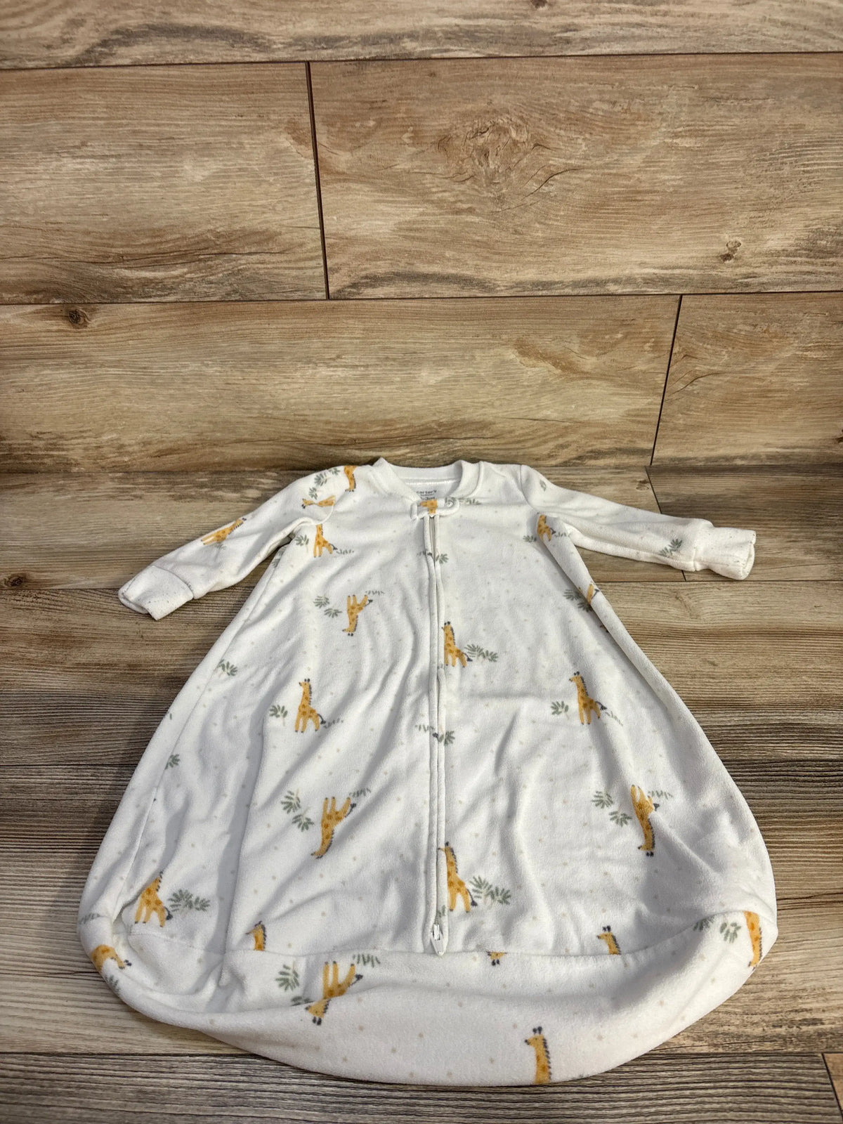 Front view of Carter’s white blanket sleep sack showcasing giraffe print and front zipper on wood floor