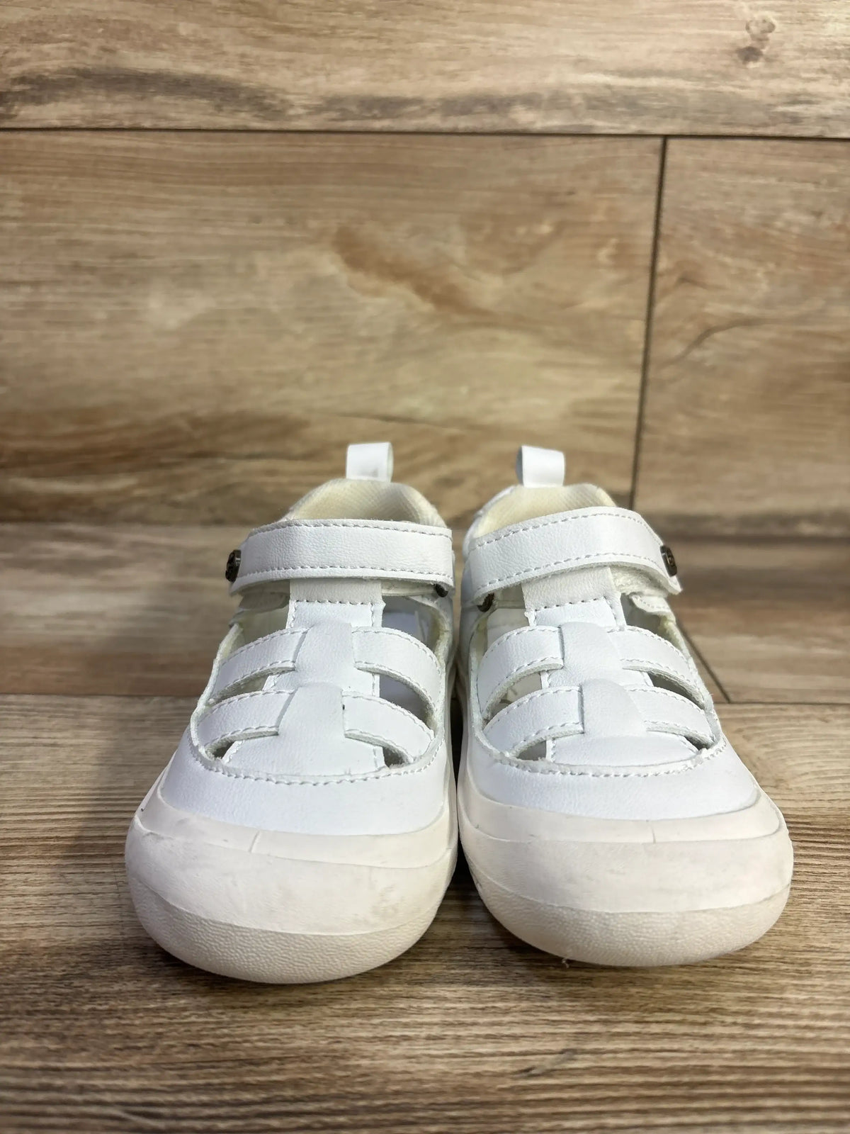 Front view of Bearpaw toddler fisherman sandals size 6C with white woven straps, Velcro closure, and rubber toe bumper on wood floor