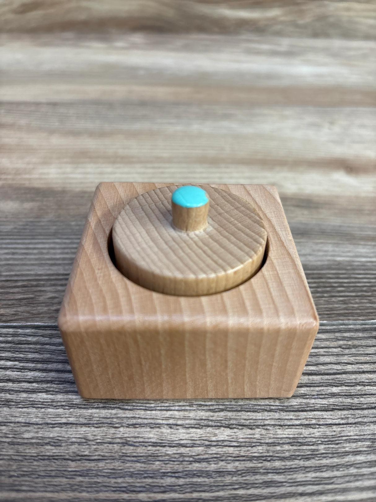 Montessori wooden knobbed cylinder with blue top on wood grain background