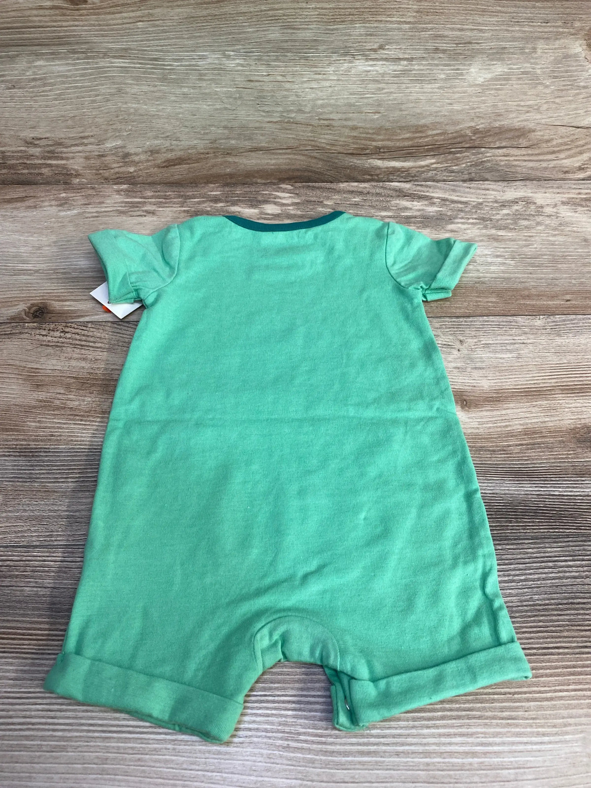 Back view of Cat and Jack shortie romper in green showing short sleeves, rolled cuffs, and snap crotch on light wood background