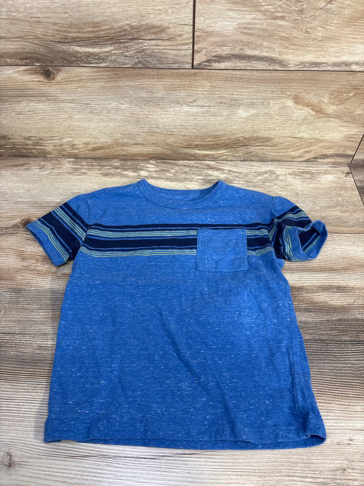 Front view of Cat & Jack striped pocket shirt in blue, size 5T, showcasing short sleeves and chest pocket with wood-look background