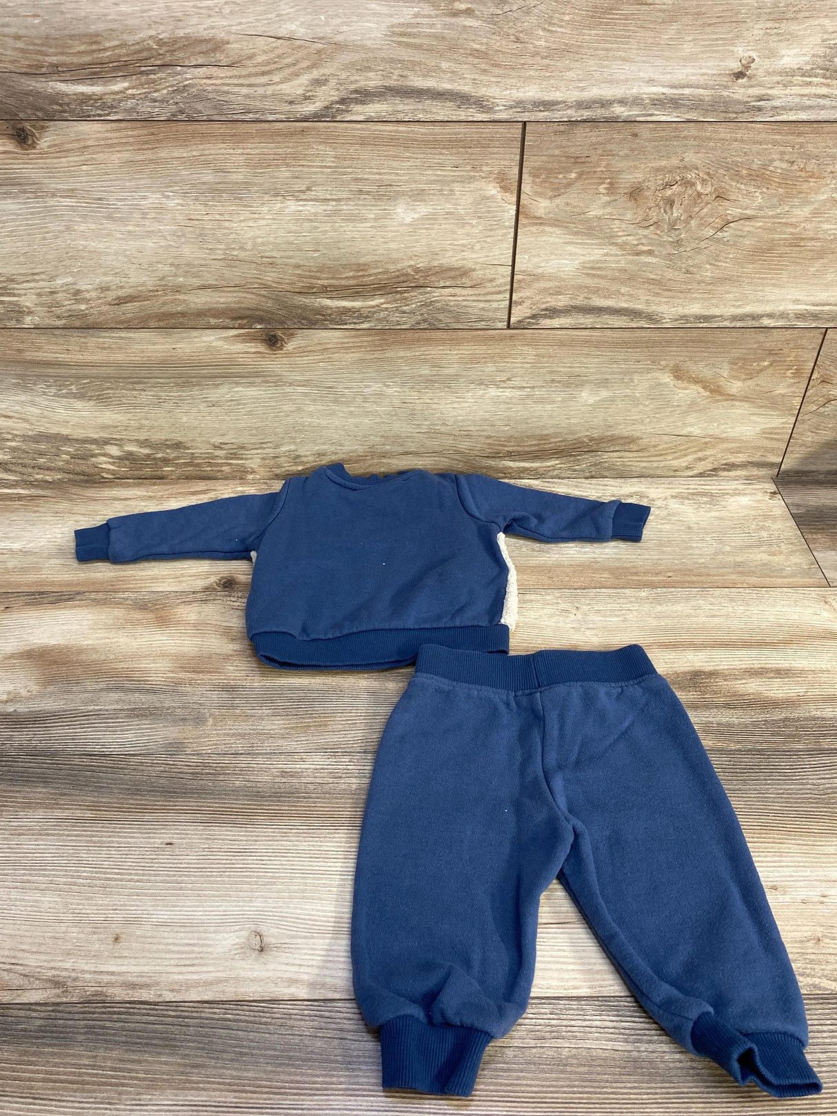 Blue fleece toddler outfit with long-sleeve top and elastic cuff pants on wooden floor