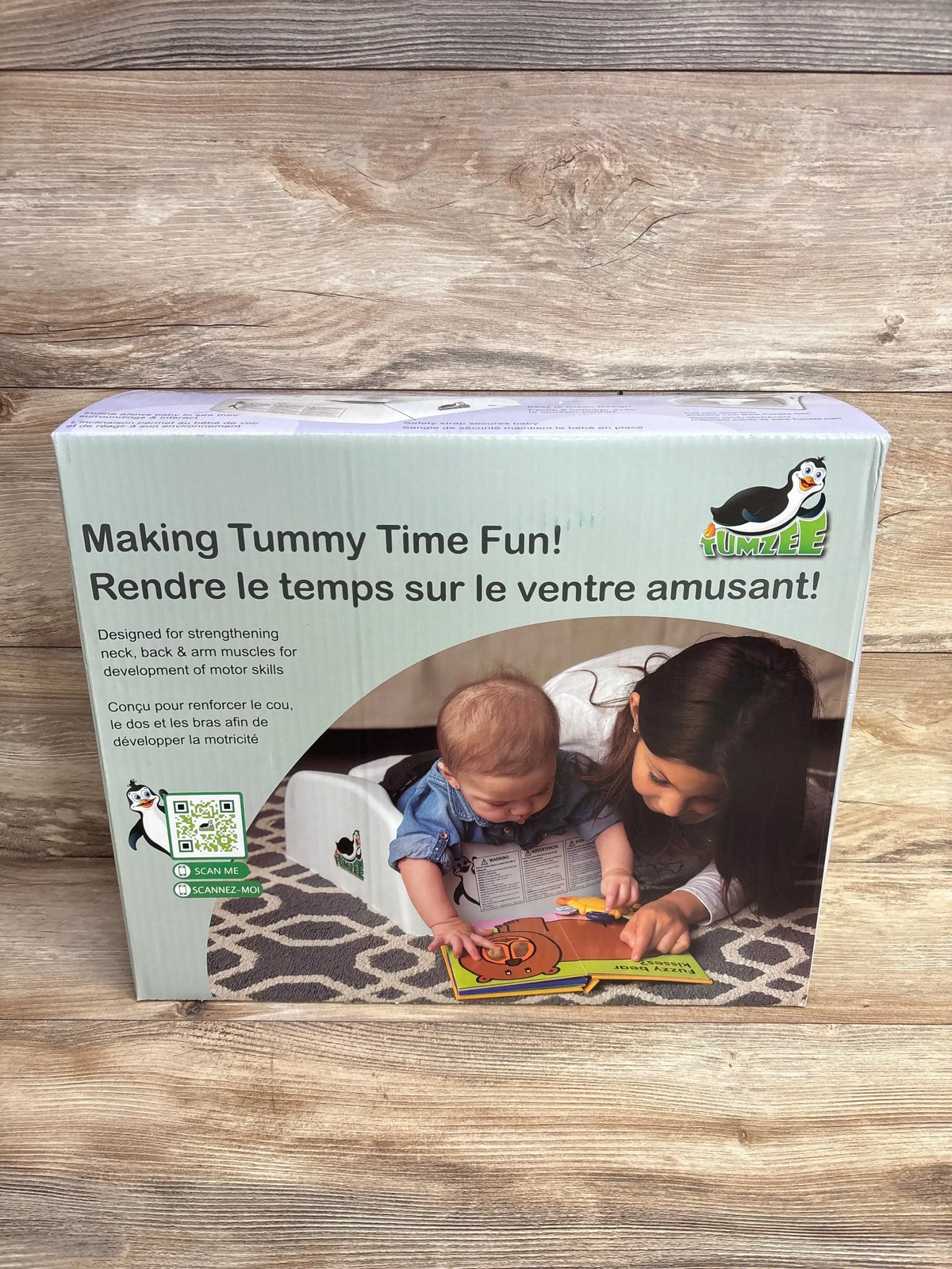 Front of NEW Tumzee Tummy Time Incline Tool packaging with headline Making Tummy Time Fun showing baby on wedge and child reading on patterned rug