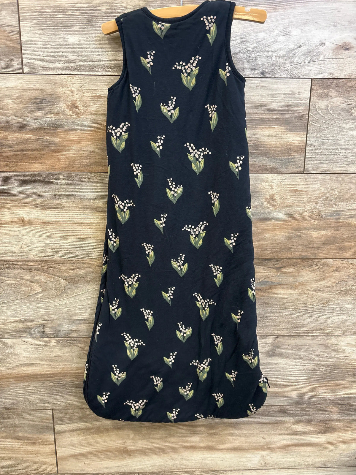 Front view of Kyte Baby 2.5 TOG bamboo sleep bag in black size M showcasing floral print on wood floor