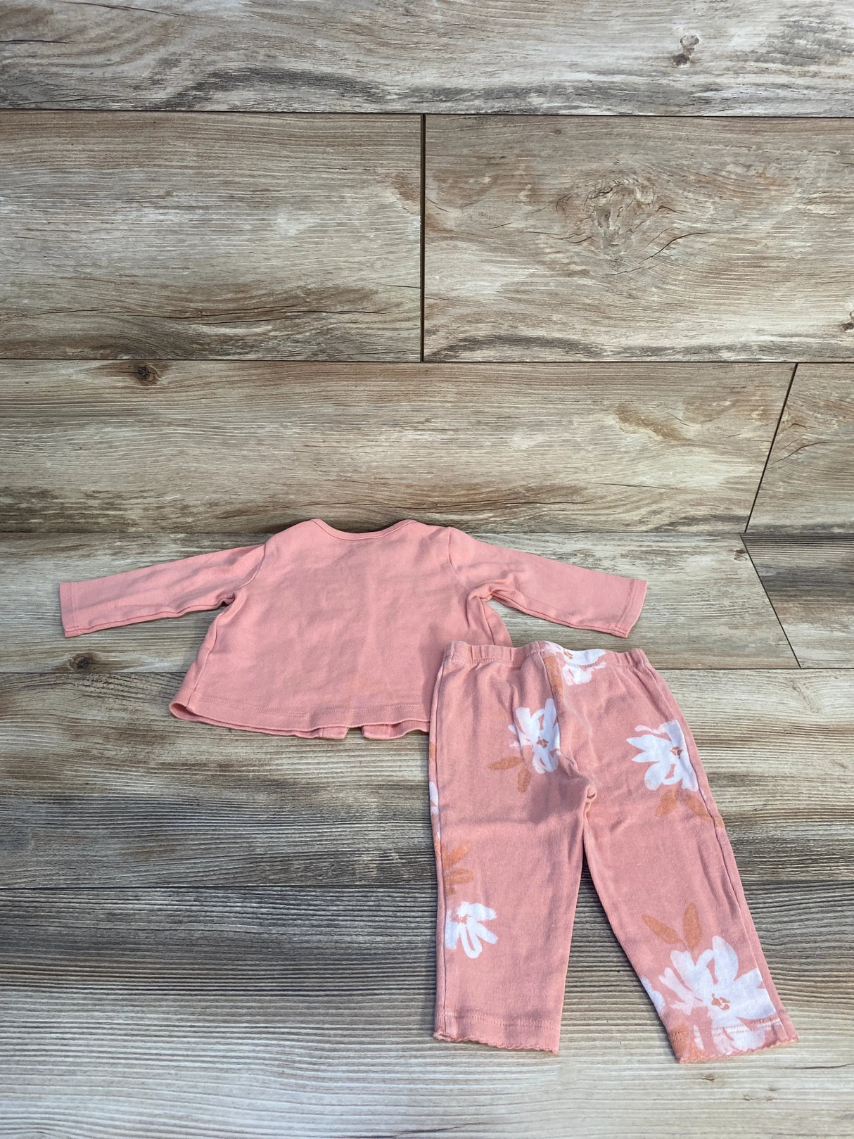 Flat lay of Carter's pink long sleeve top and floral pants set size 3-6 months showing elastic waist and floral print on wood background