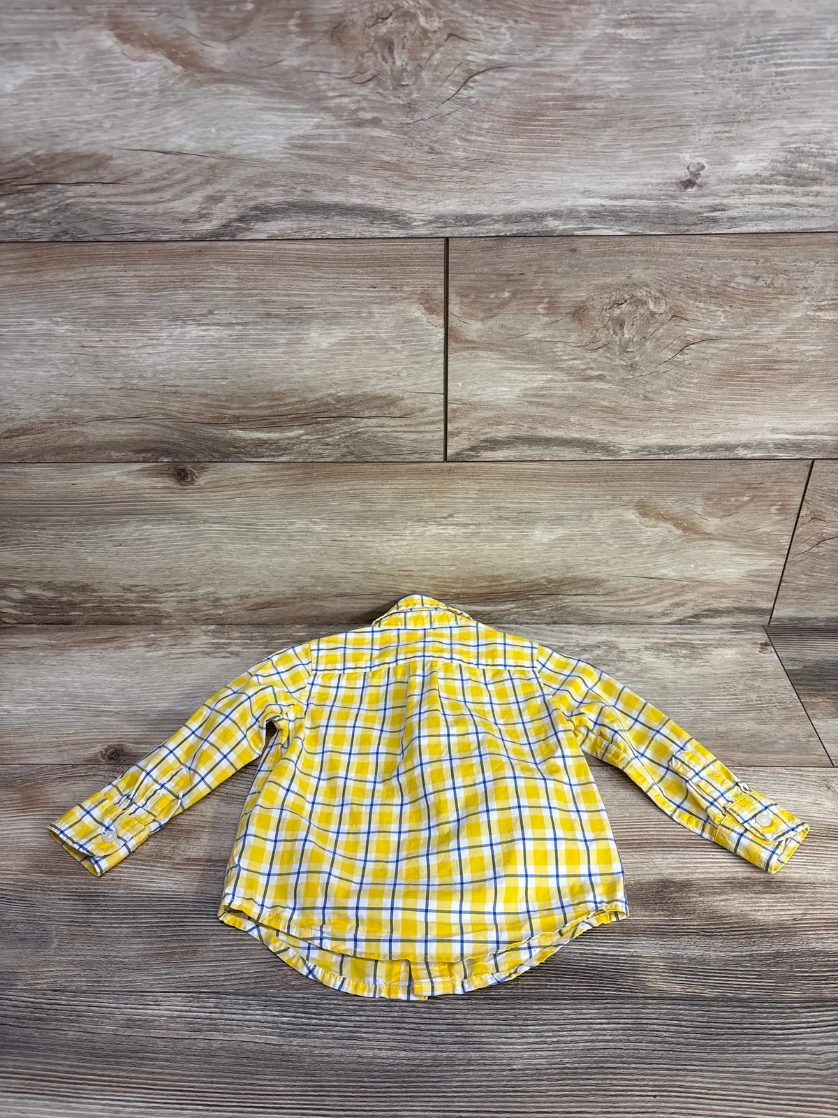 Back view of Janie & Jack yellow plaid button up shirt showcasing long sleeves and collar on a wood-grain background