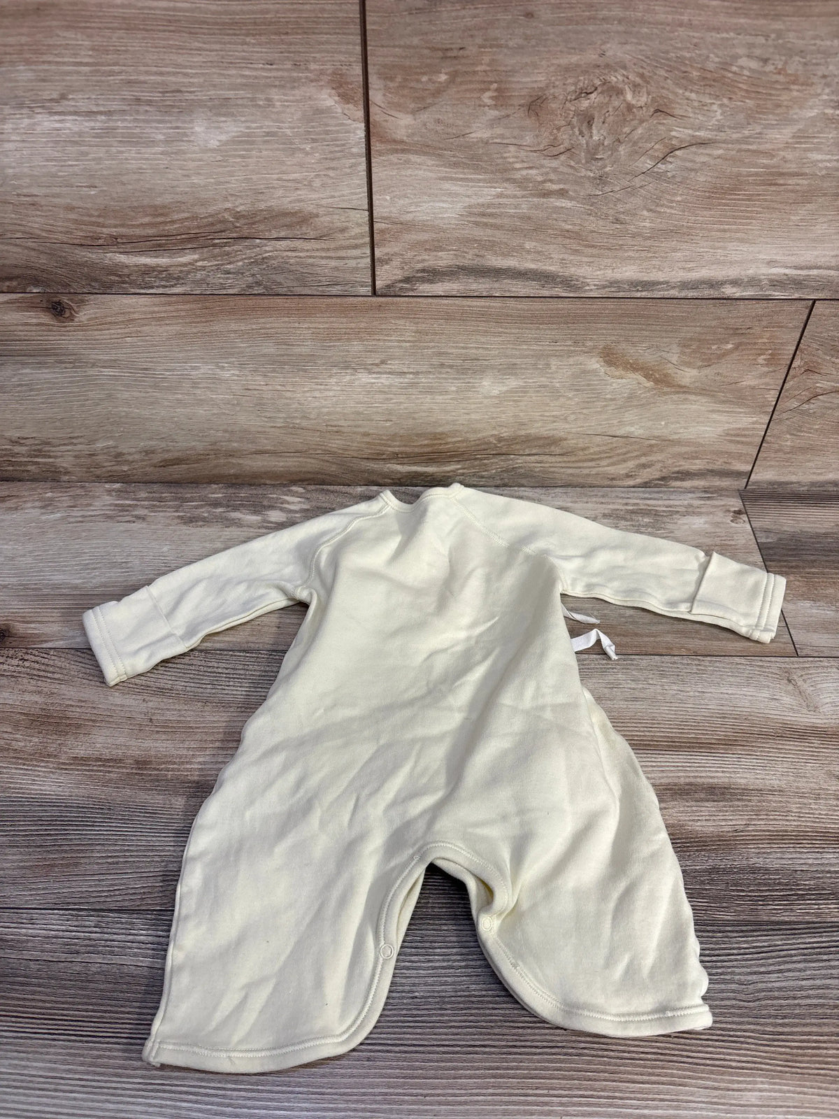 Back view of Mides Lion Kimono Romper in yellow showcasing kimono-style wrap ties and long sleeves on a wood floor