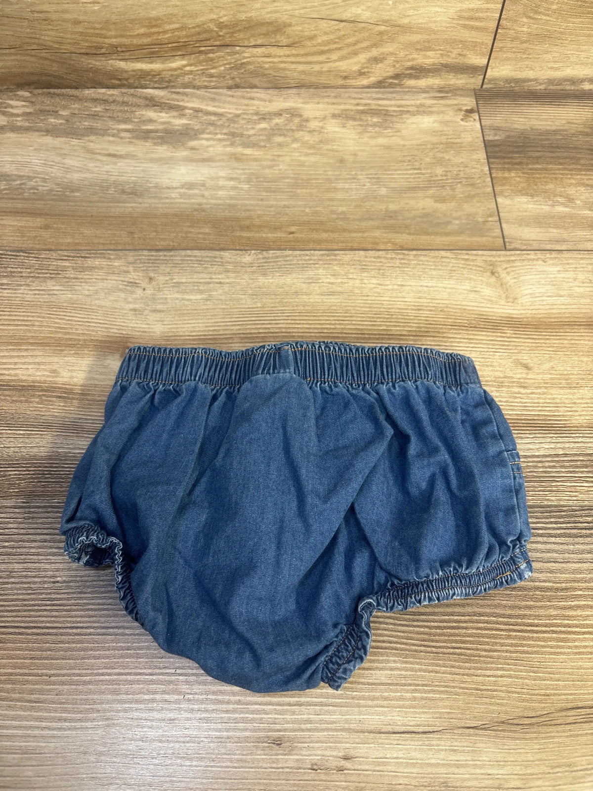 Front view of blue Cat & Jack chambray bloomers showcasing elastic waistband and leg openings with wood flooring background