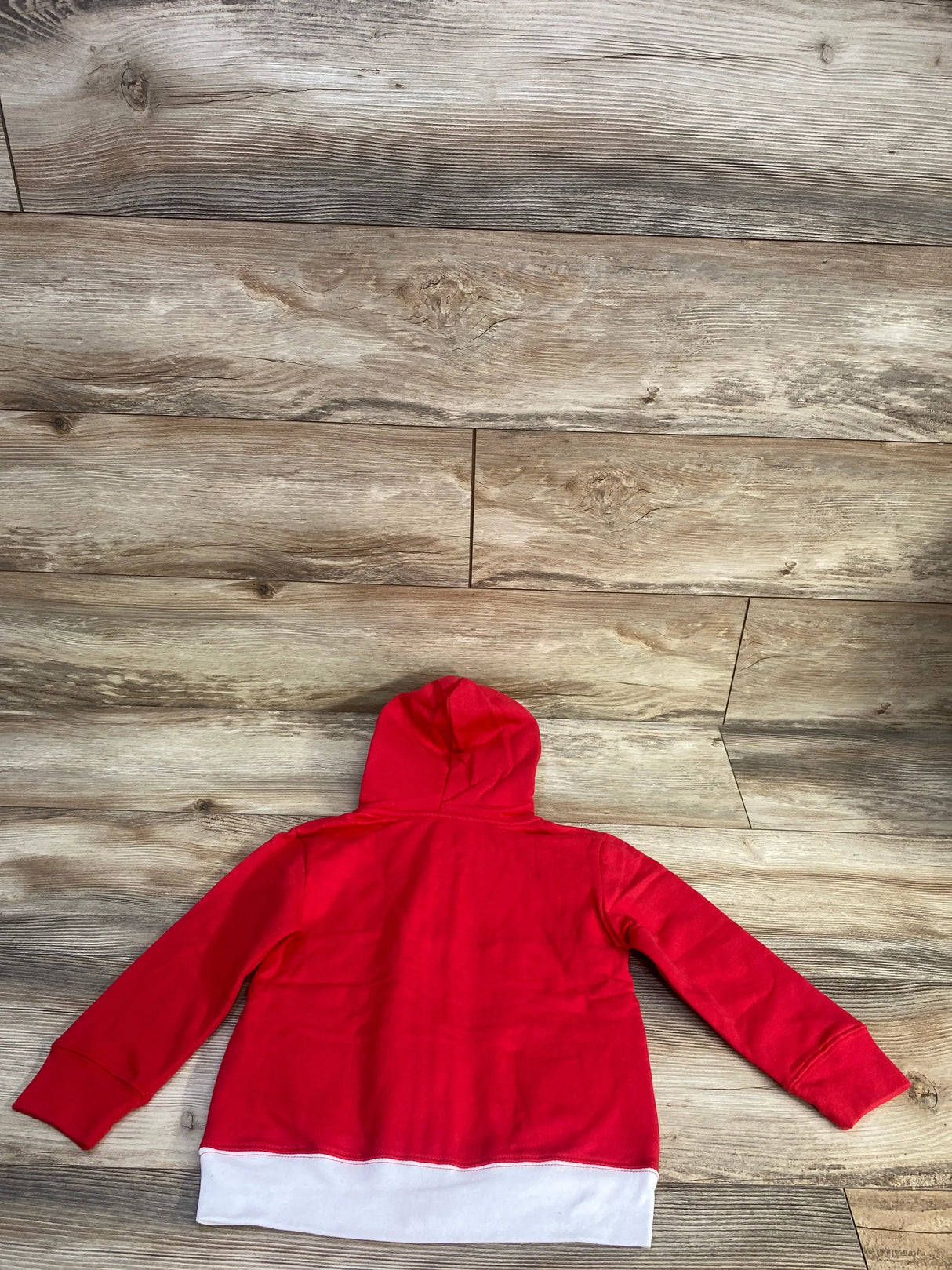 Back view of red toddler zip-up hoodie with hood and white bottom band, size 4T, laid flat on wood floor