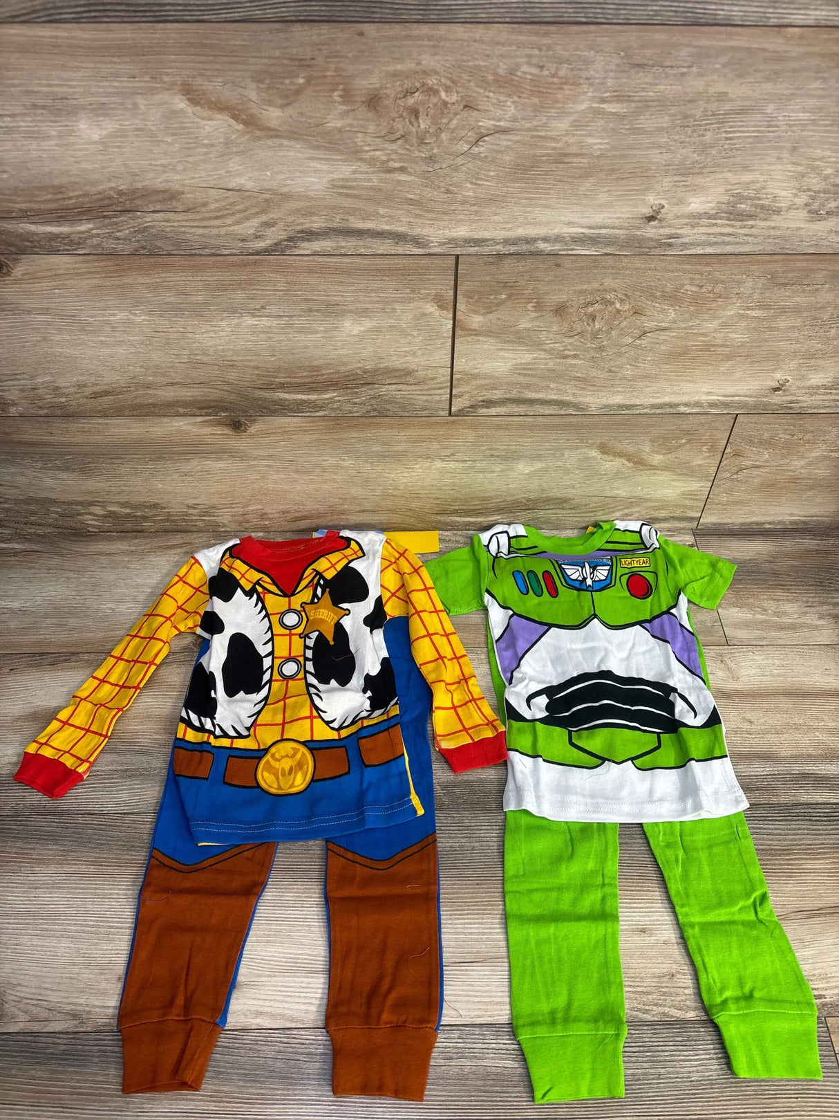 Woody and Buzz Lightyear kids pajamas on wood floor, Toy Story themed sleepwear set