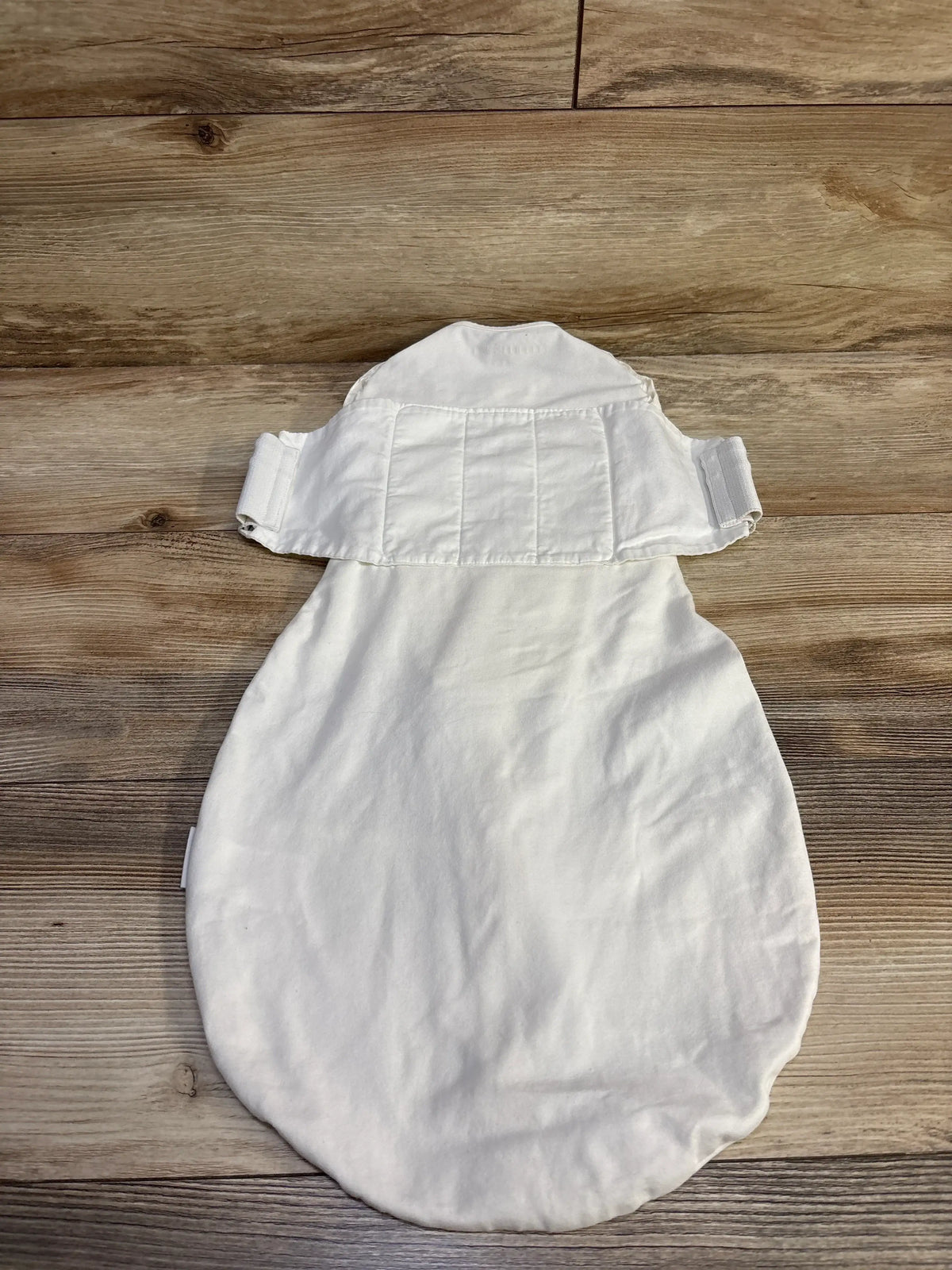 White Happiest Baby SNOO sleep sack for infants size medium, laid flat on a wooden surface.