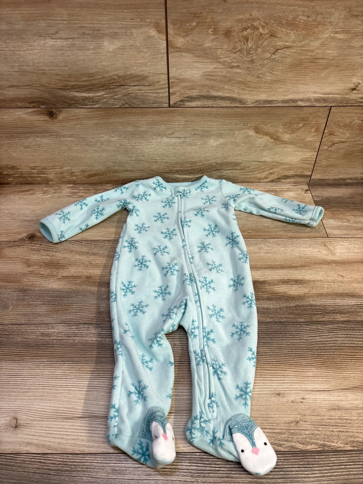 Front view of Just One You blue blanket sleeper, size 6 months, with snowflake pattern and character-face feet on wood floor