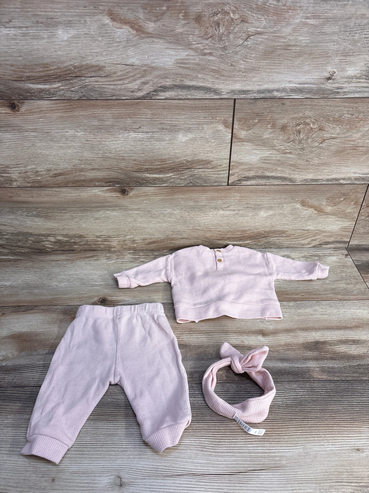 Pink baby waffle knit outfit set with top, pants, and headband on wooden floor