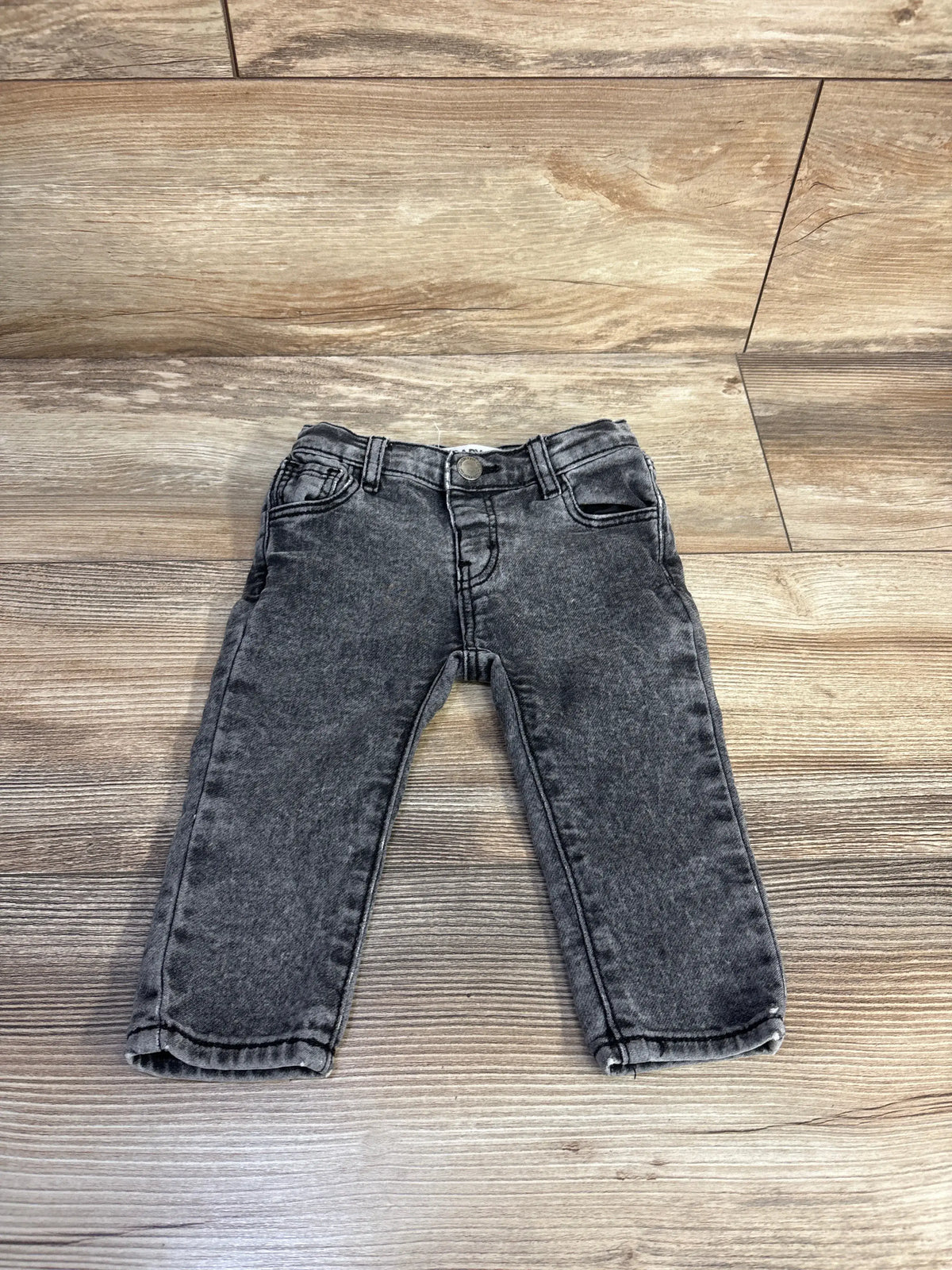 Front view of grey Cotton On baby jeans in size 6-12 months showcasing five-pocket styling on a wood-look floor