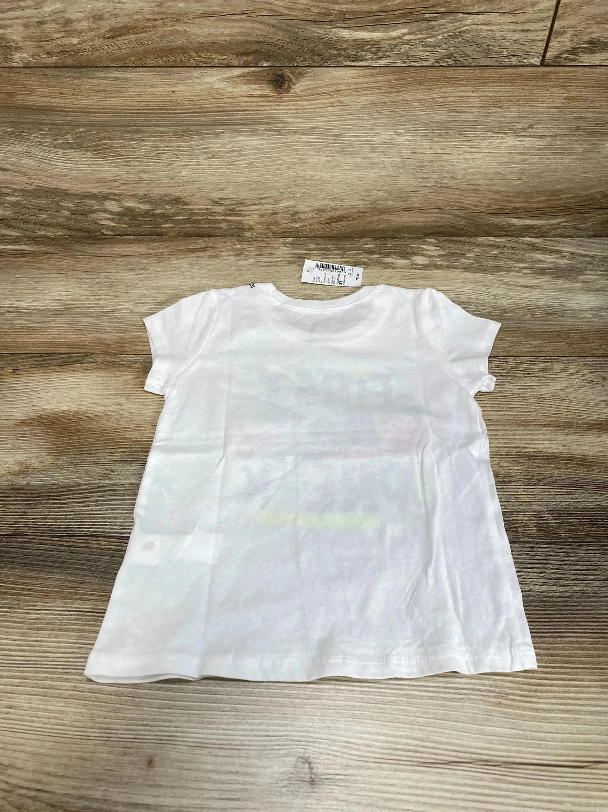Back view of Children's Place white toddler T-shirt, size 3T, showing short sleeves and crew neck on wood background