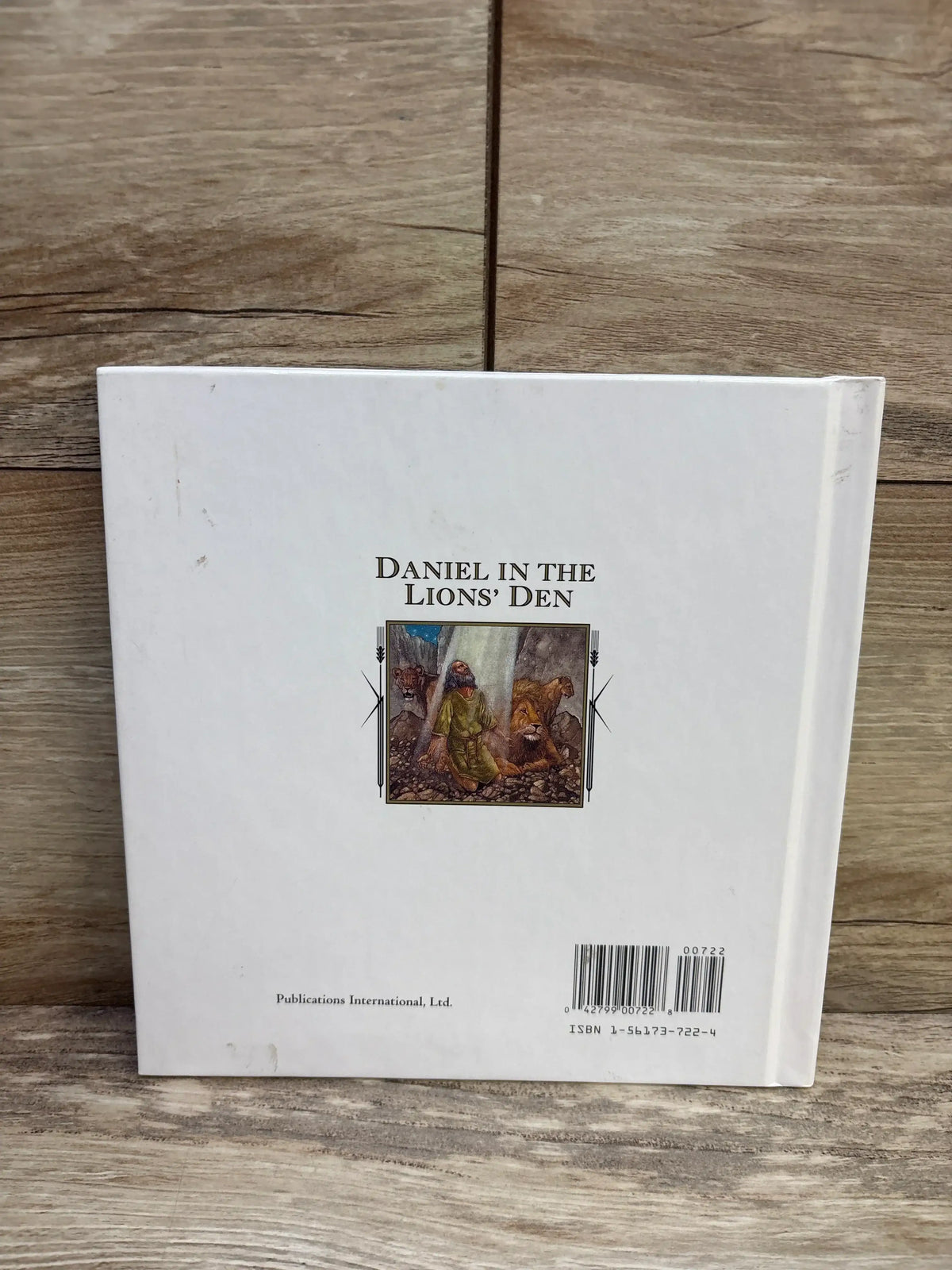 Back cover of Daniel In The Lions Den hardcover book showcasing title with illustration and barcode on wood plank floor