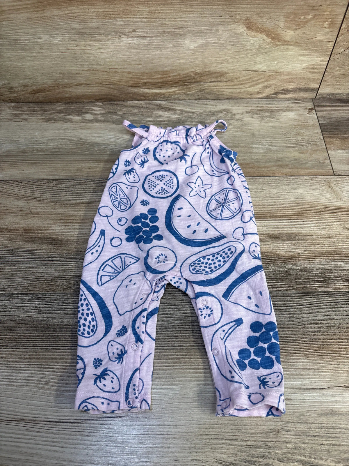 Front view of Cat & Jack pink sleeveless jumpsuit with fruit pattern laid flat on a wood floor