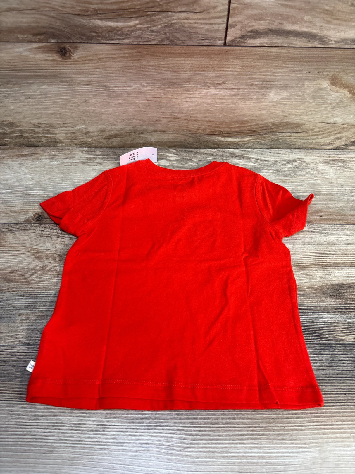 Back view of red Baby Gap Popsicle toddler t-shirt (size 3T) showing plain back and crew neckline on wood-plank background