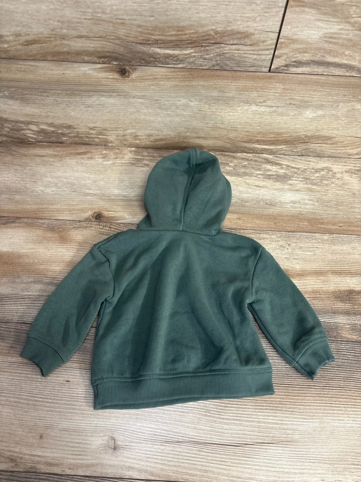 Back view of Little Co pullover hoodie showcasing solid green fleece with attached hood on wood plank floor