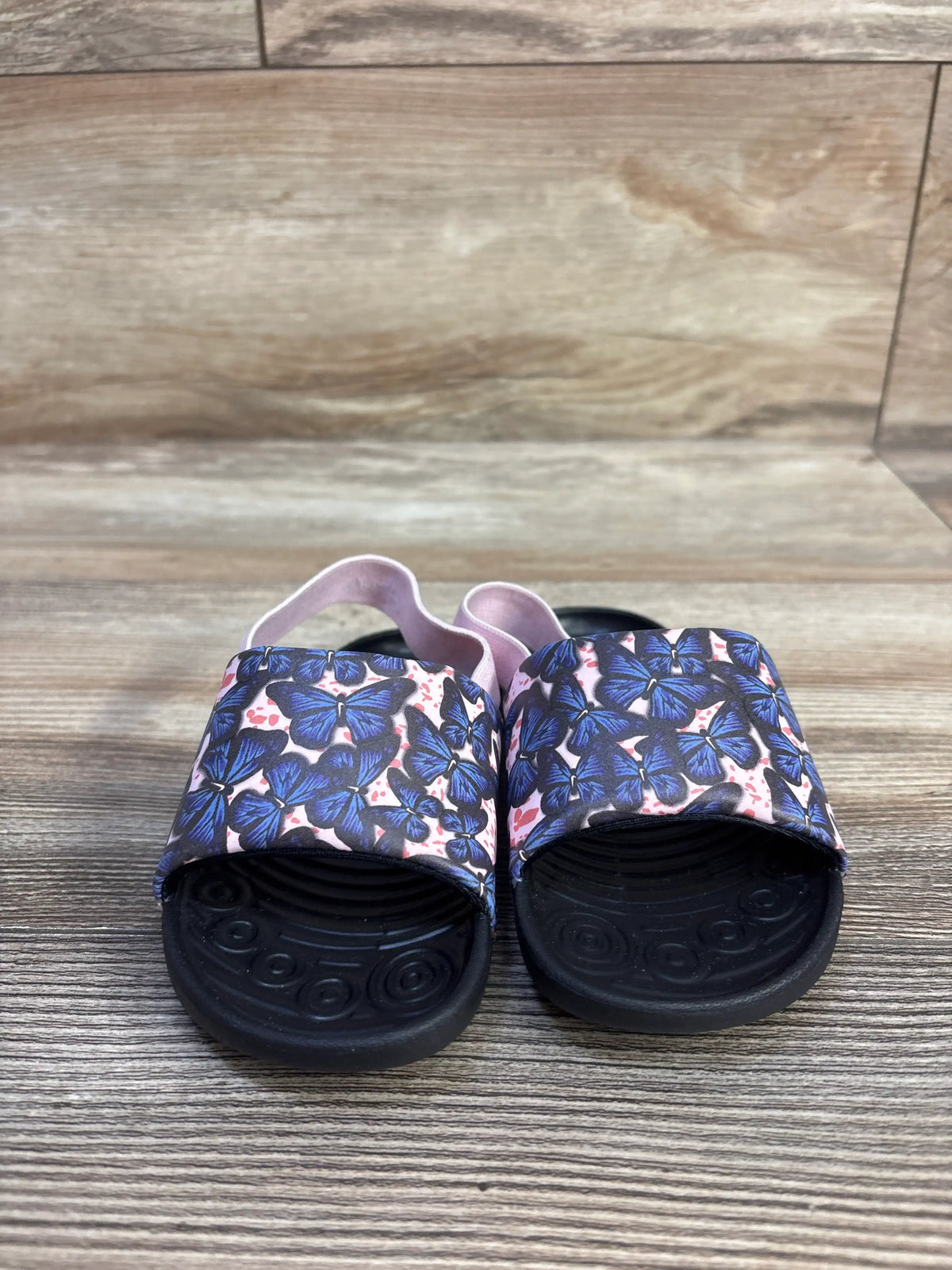 Front view of Nike Kawa TD Pink Foam Butterfly slides showcasing blue butterfly print, black soles, and pink heel straps