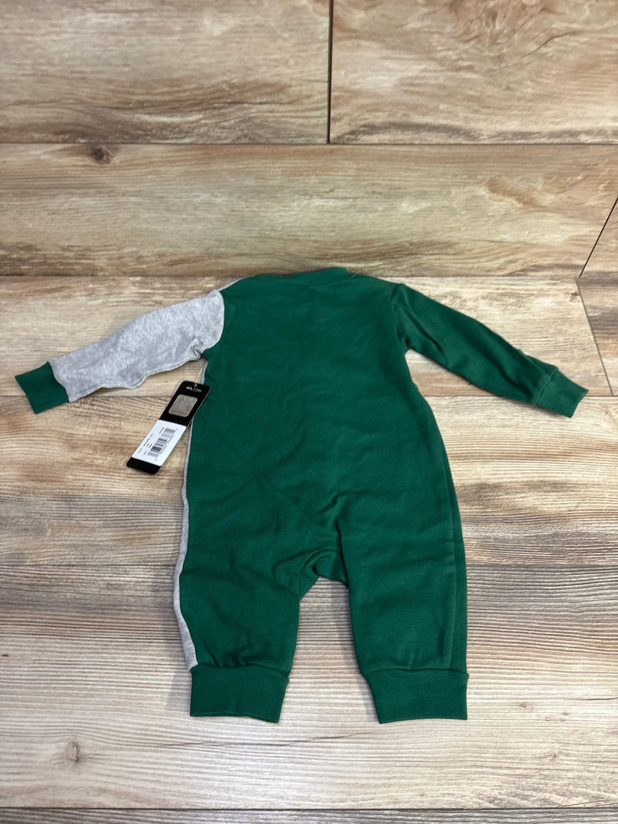 Back view of green and gray long sleeve toddler jumpsuit on wooden floor with price tag