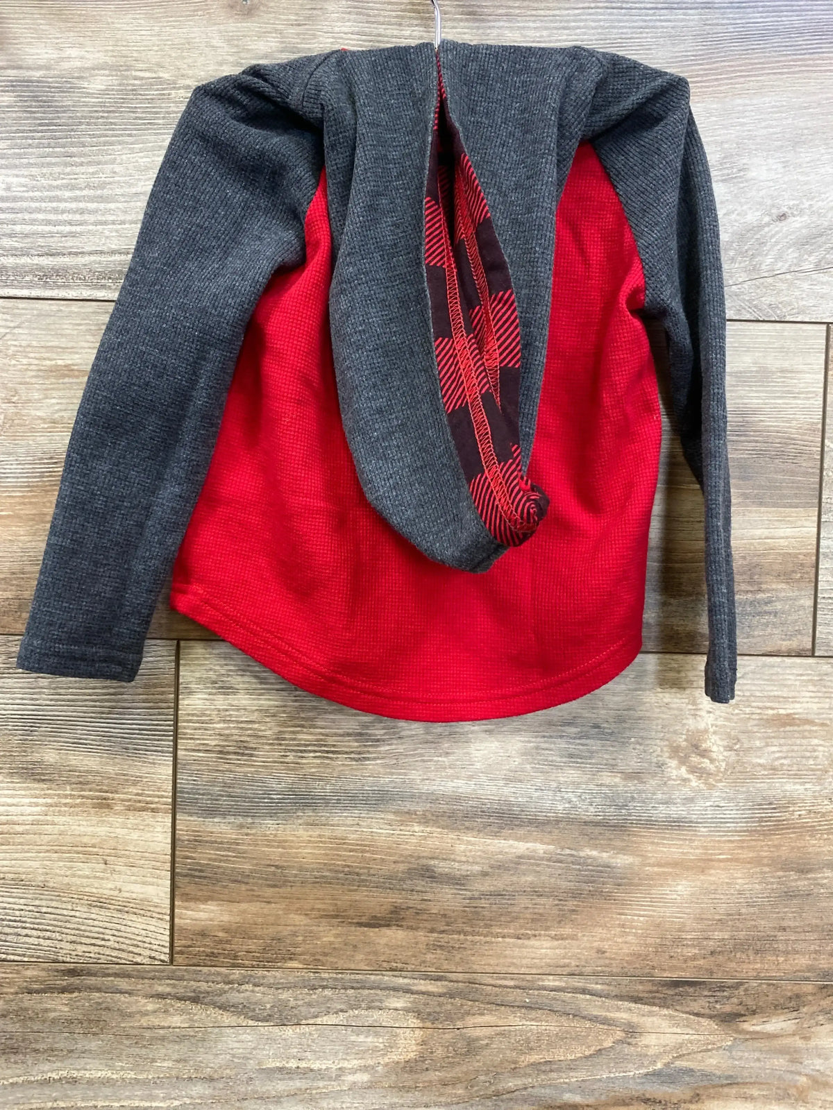Red and gray long sleeve kids shirt with buffalo plaid detail on wooden background