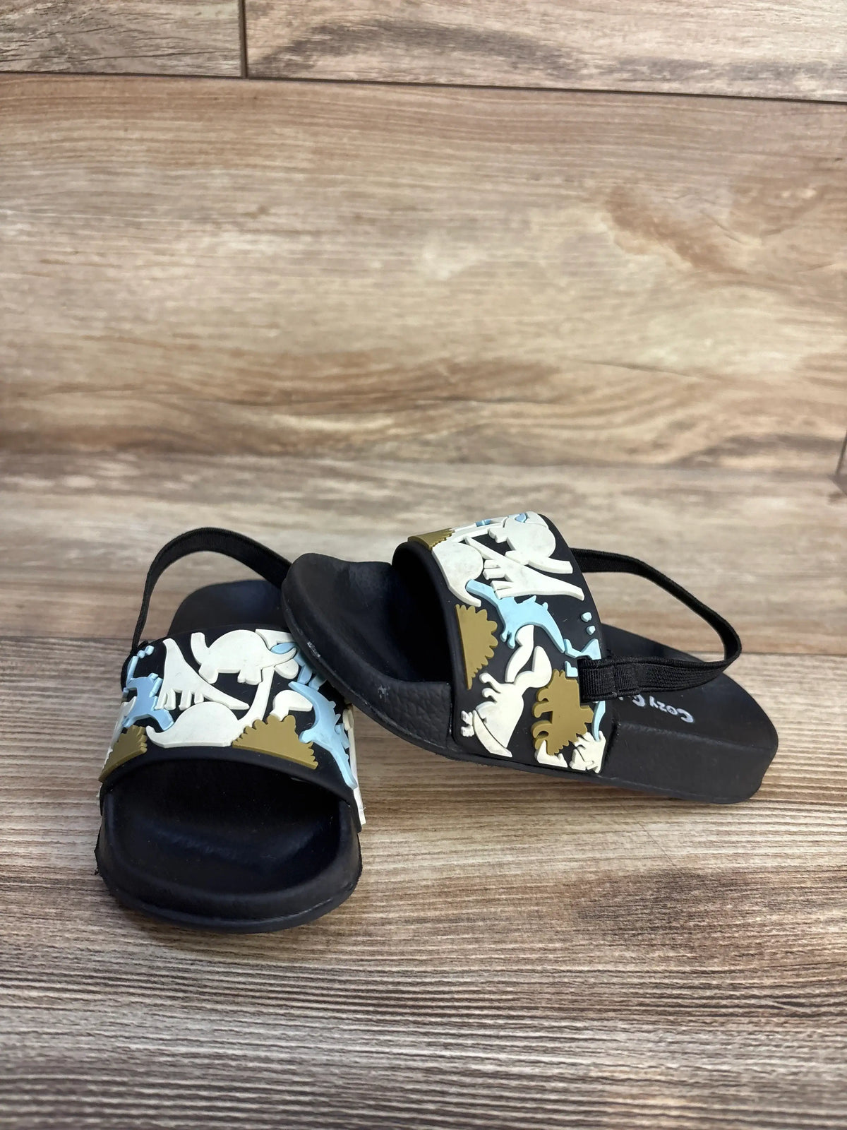 Cozy Cub dinosaur slide sandals in black with colorful dino graphics