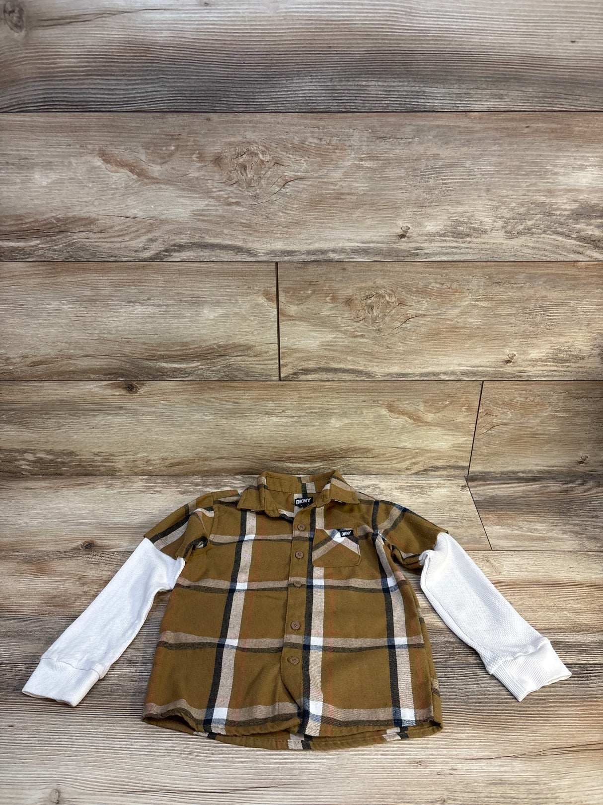 DKNY toddler plaid button-up shirt with white long sleeves, laid on wood floor
