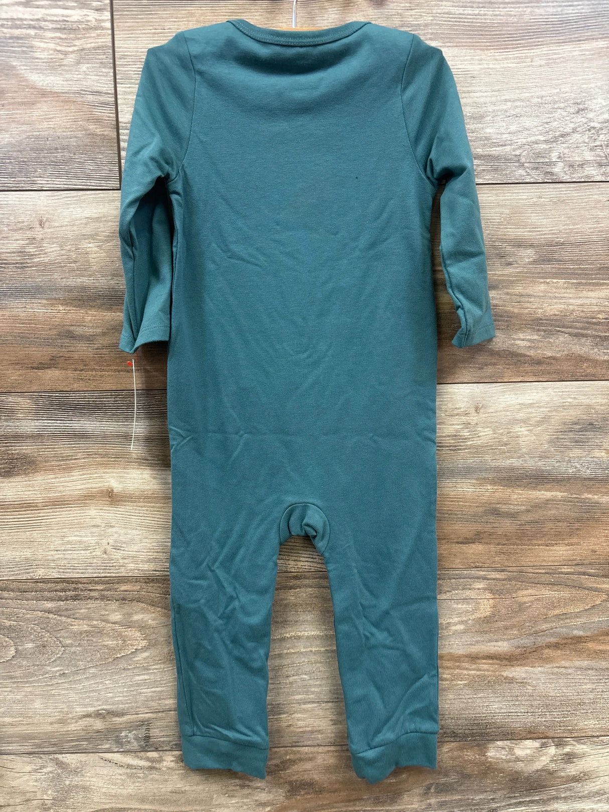 Green long sleeve baby romper laid flat on wooden background
