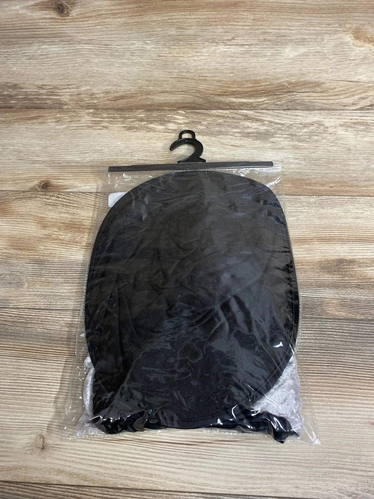 Top-down view of black Abraham Lincoln stovepipe hat in clear plastic packaging with hanger on wood background