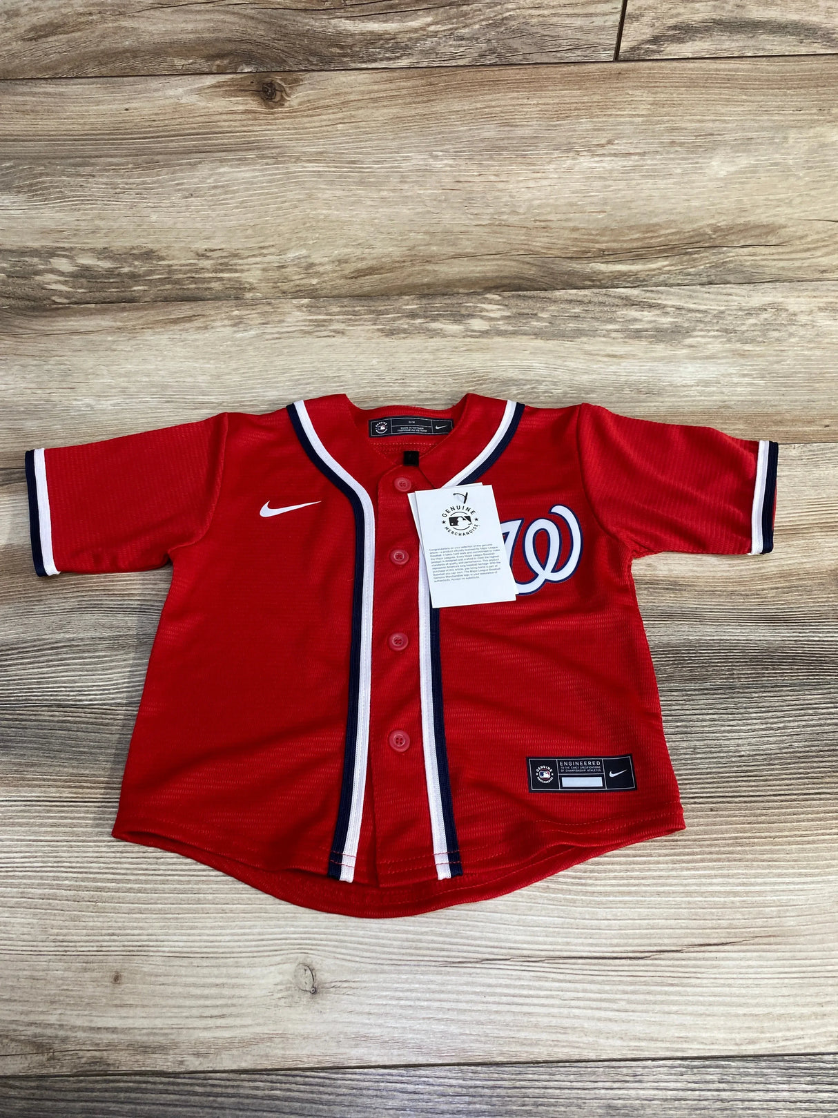 Flat lay of toddler red Washington Nationals replica jersey, button-front with W logo and Nike swoosh on wood background