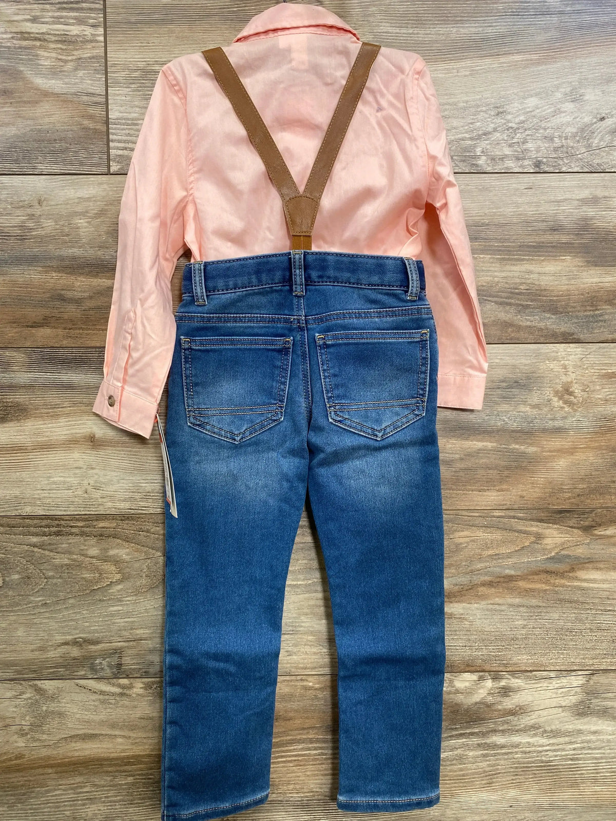 Back of Cat and Jack suspender set: pink long-sleeve shirt, blue jeans and brown suspenders on wood floor