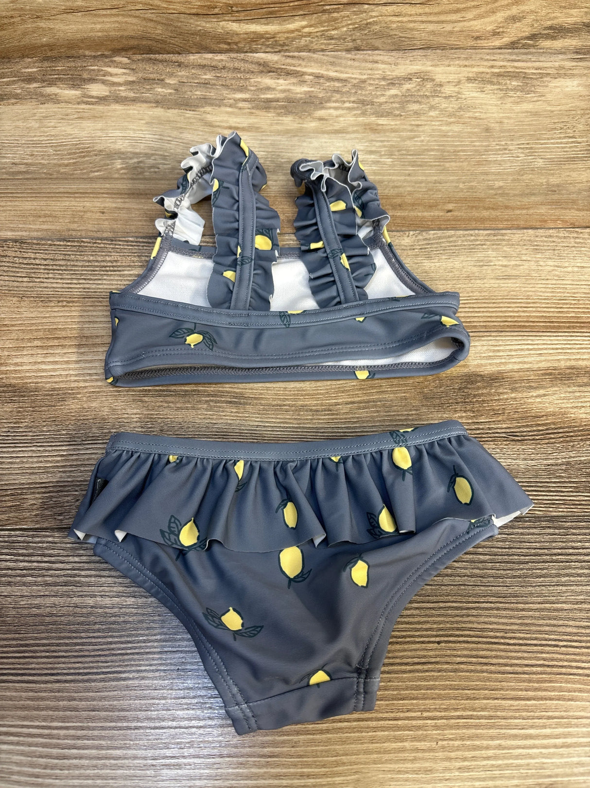 Gray toddler bikini with yellow lemon print and ruffled straps on wood background