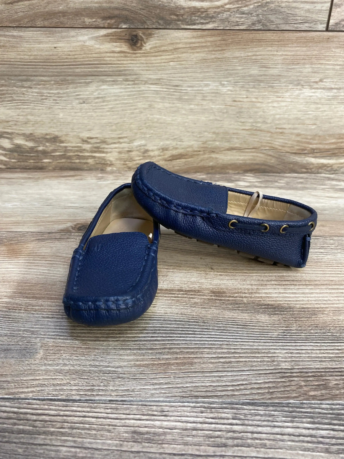 Side view of Janie and Jack Leather Driving Shoe Navy sz 8c showcasing navy pebbled leather moccasins with stitched detail on wood plank floor