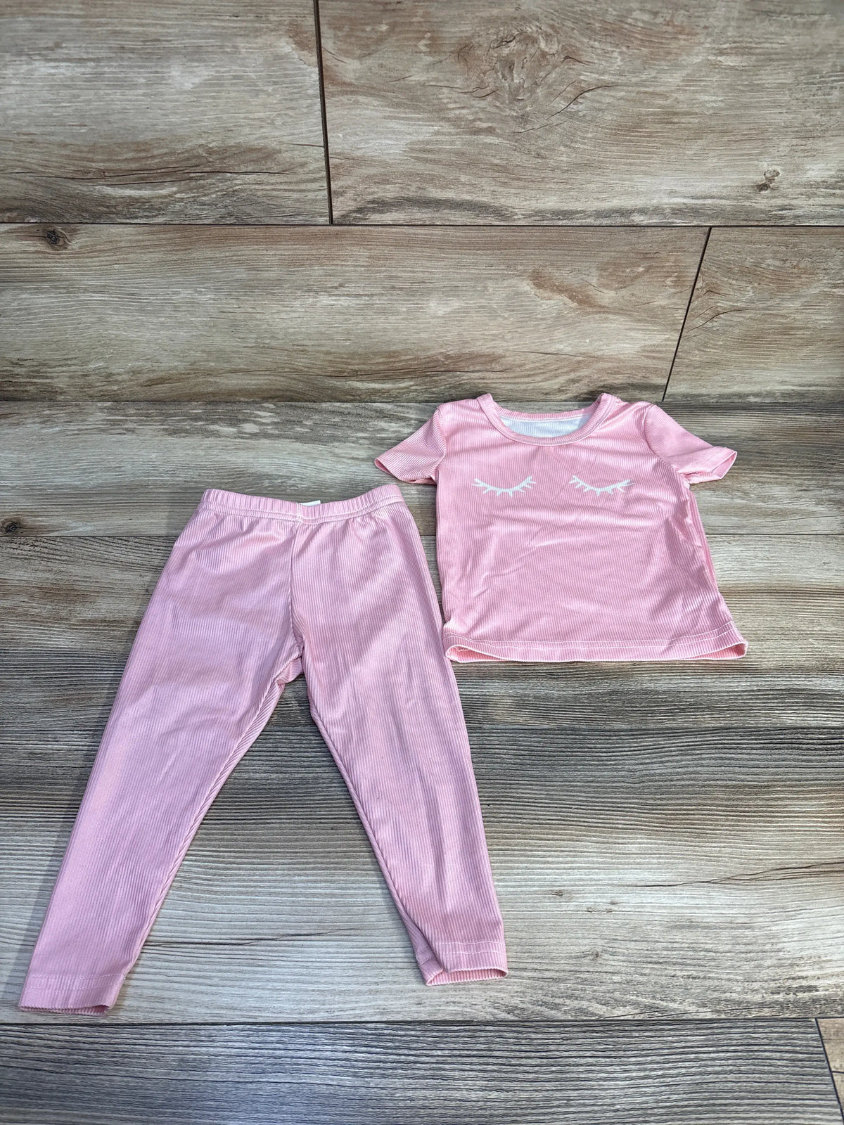 Top-down view of Shein pink ribbed pajama set showcasing short-sleeve top and elastic-waist pants on wood flooring