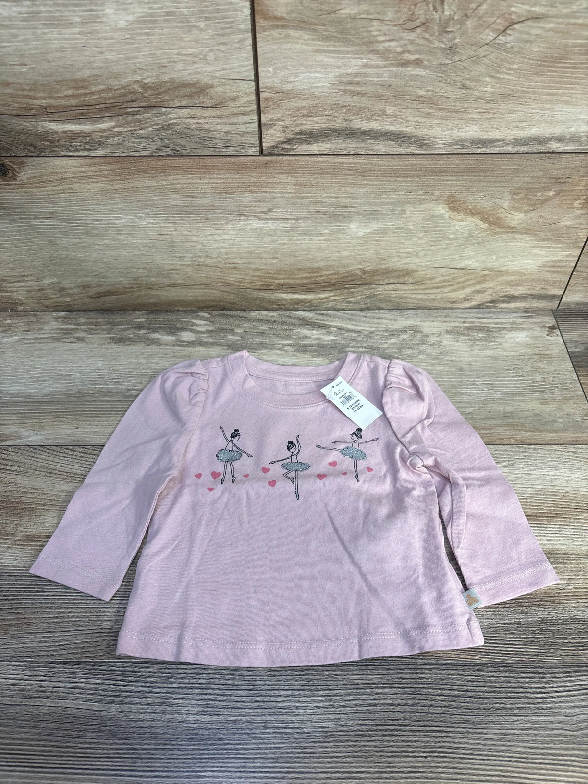 Front view of Baby Gap pink ballerina shirt for 6–12 months with puff sleeves and ballerina graphic on wood background