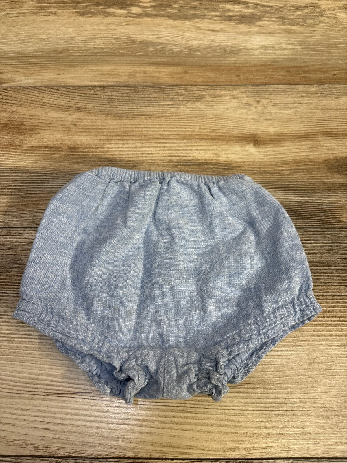 Janie & Jack blue chambray bloomer shorts for infants on a wooden background