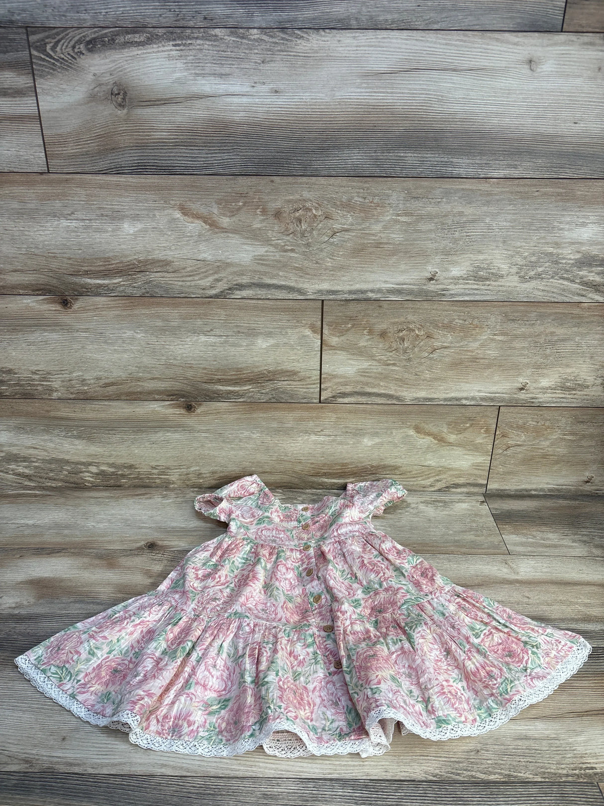 Front flat lay of girls Joie floral tiered dress size 3T showing button-front, ruffled cap sleeves, tiered skirt and lace trim on wood floor