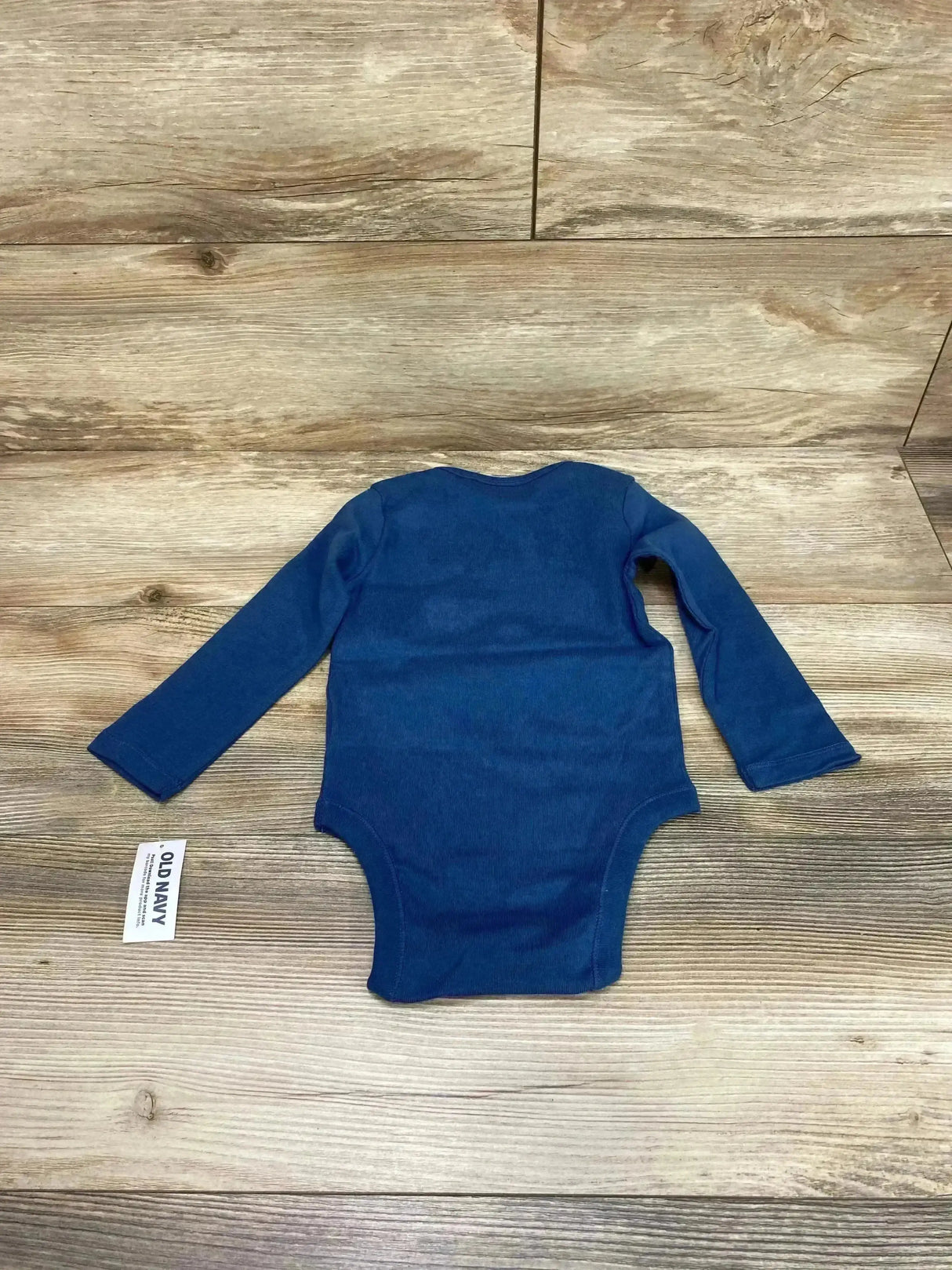Flat lay of Old Navy blue long-sleeve baby bodysuit (18–24 months) showing back view and snap bottom on wood background