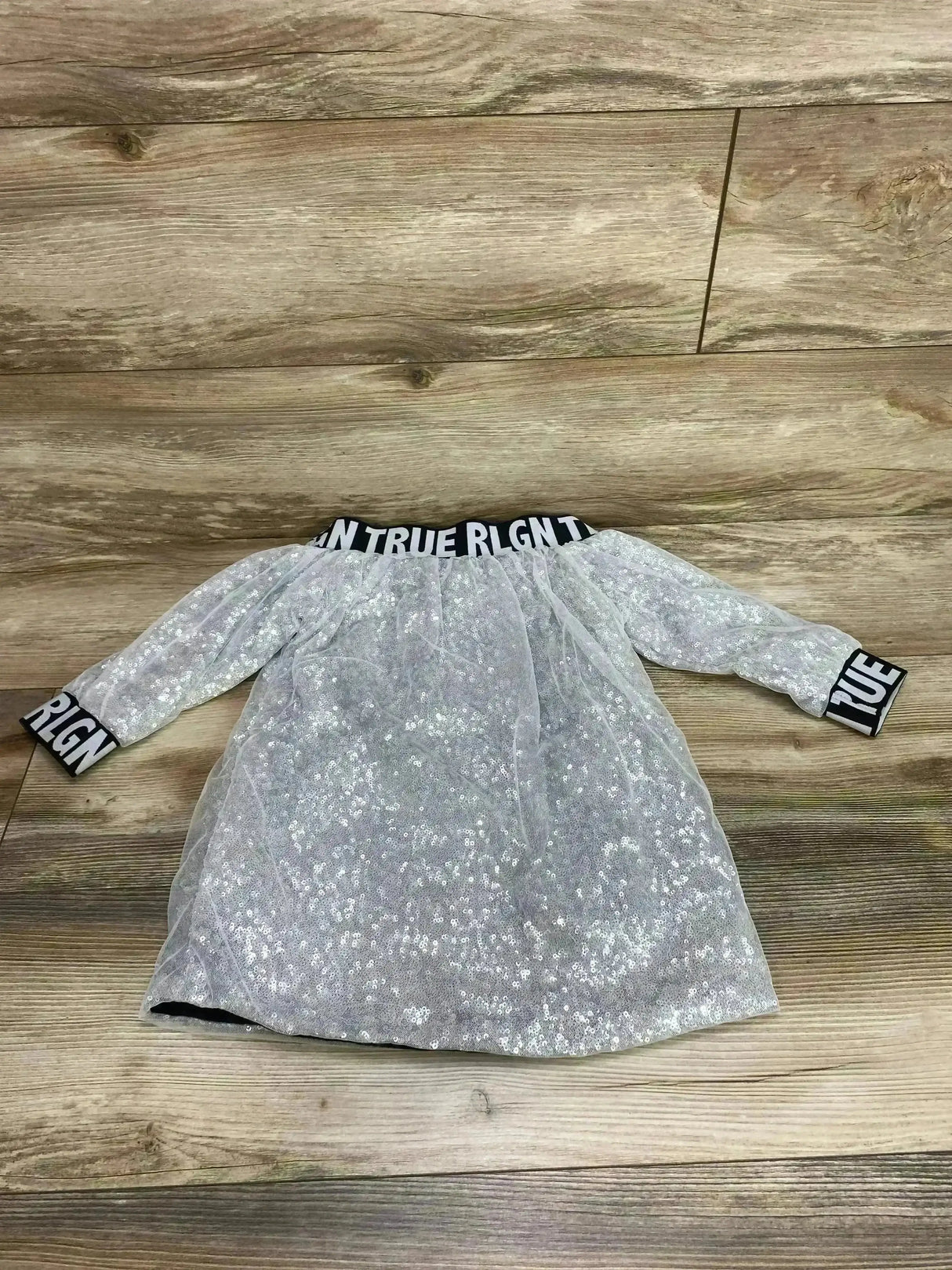 Flat-lay True Religion silver sequin long-sleeve dress size 2T with TRUE RLGN elastic neckline and cuffs on wood